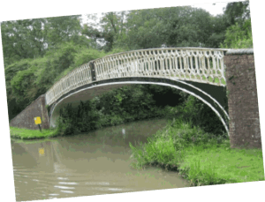 A picture of a black iron bridge with white railings over a canal.